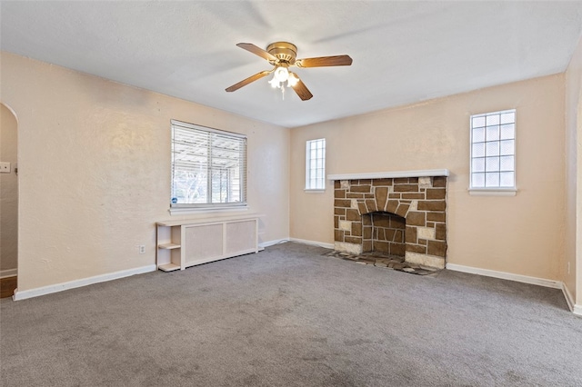 unfurnished living room featuring a stone fireplace, radiator heating unit, carpet floors, and a healthy amount of sunlight