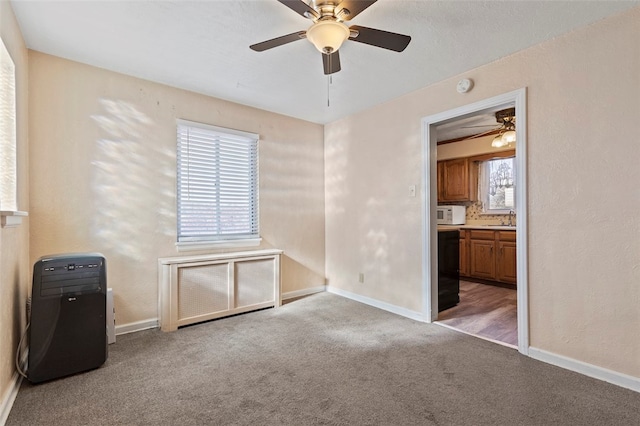 empty room with sink, light colored carpet, and ceiling fan