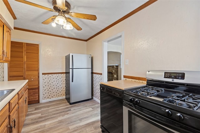 kitchen with stainless steel appliances, ceiling fan, crown molding, and light hardwood / wood-style flooring