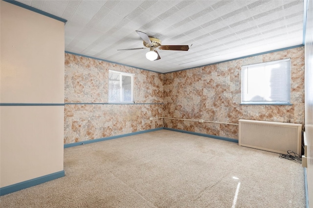 empty room featuring ornamental molding, radiator, ceiling fan, and carpet floors