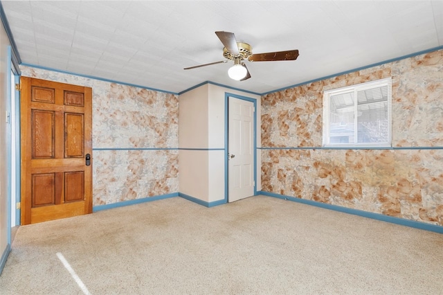 carpeted spare room featuring ceiling fan and crown molding