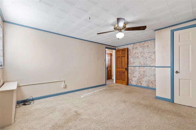 carpeted empty room featuring ceiling fan and crown molding