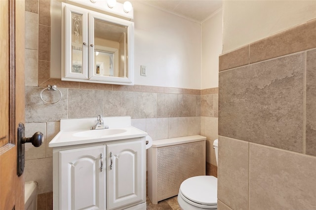 bathroom with tile walls, radiator heating unit, vanity, and toilet