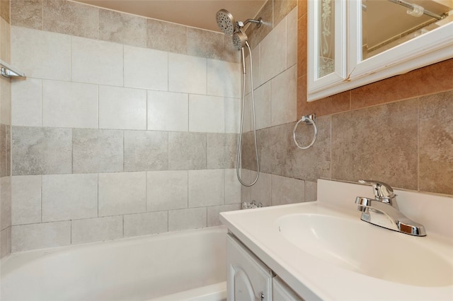 bathroom with tile walls, tiled shower / bath, and vanity