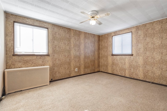 unfurnished room with radiator heating unit, ceiling fan, and light colored carpet