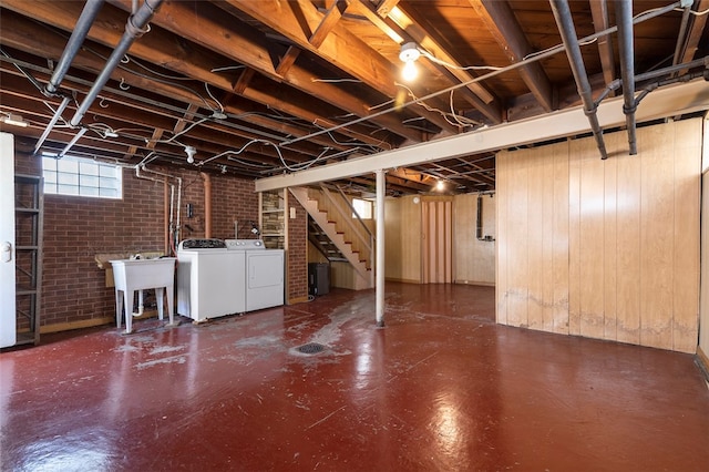 basement with wood walls, brick wall, sink, and independent washer and dryer