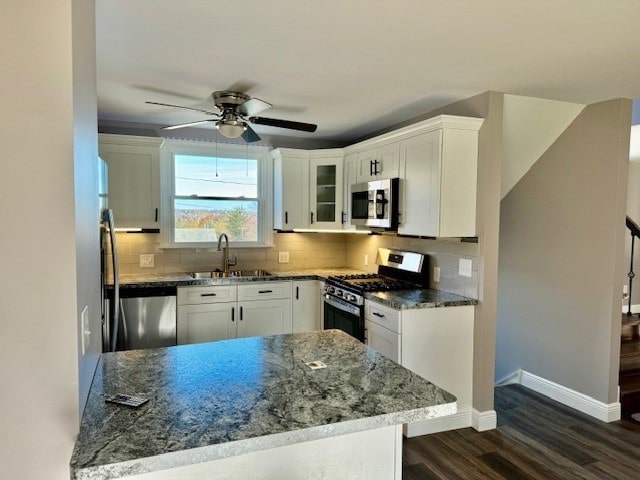 kitchen with stainless steel appliances, white cabinets, and dark stone counters