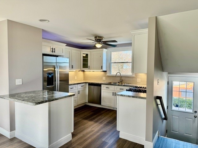 kitchen featuring dark hardwood / wood-style flooring, dark stone counters, kitchen peninsula, white cabinetry, and appliances with stainless steel finishes