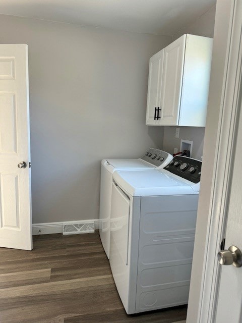 laundry room with dark hardwood / wood-style flooring, cabinets, and separate washer and dryer