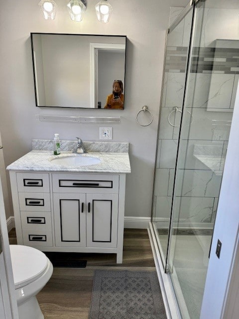 bathroom with a shower with door, wood-type flooring, toilet, and vanity