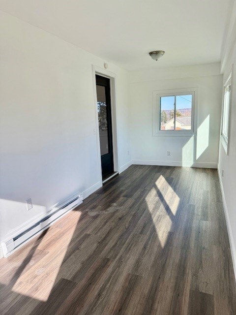 empty room with dark hardwood / wood-style floors and a baseboard heating unit