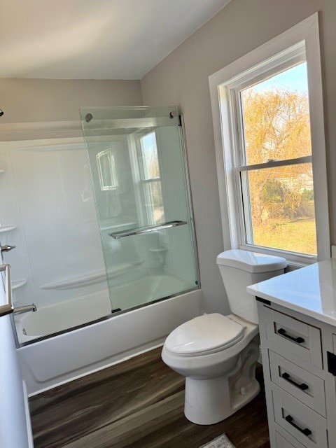 full bathroom with toilet, vanity, hardwood / wood-style floors, and enclosed tub / shower combo