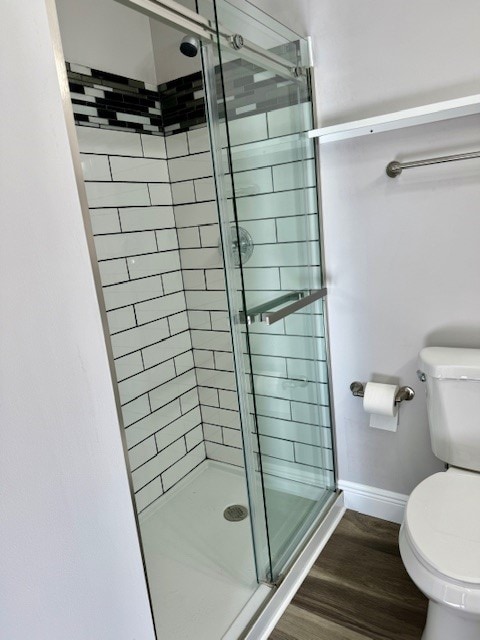 bathroom with toilet, wood-type flooring, and a shower with door