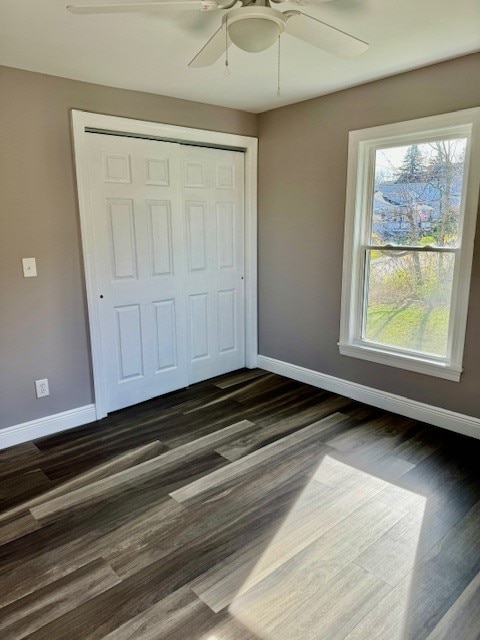 unfurnished bedroom with dark hardwood / wood-style floors, ceiling fan, and a closet