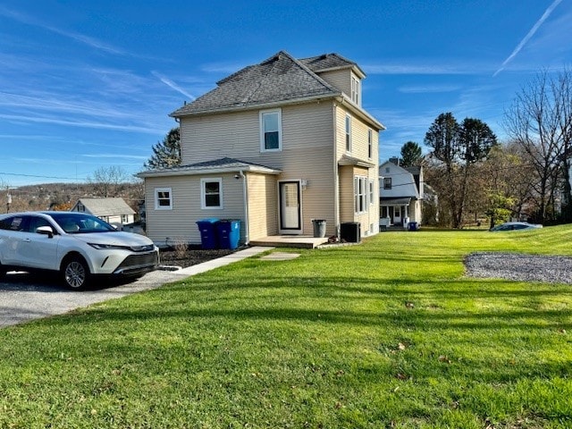 back of house with central AC and a lawn