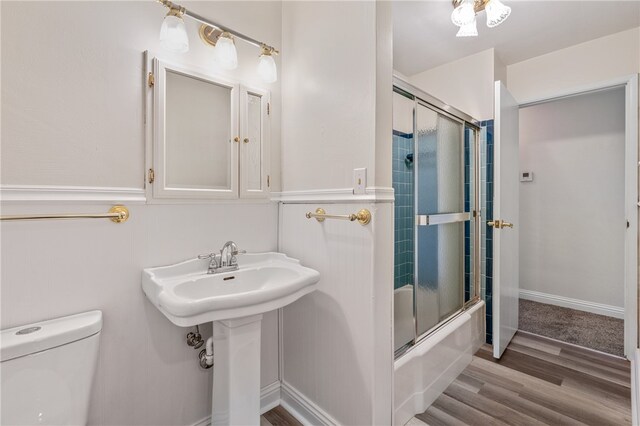 full bathroom with hardwood / wood-style floors, combined bath / shower with glass door, toilet, and sink