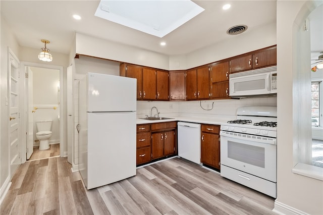 kitchen featuring pendant lighting, white appliances, sink, and light hardwood / wood-style flooring