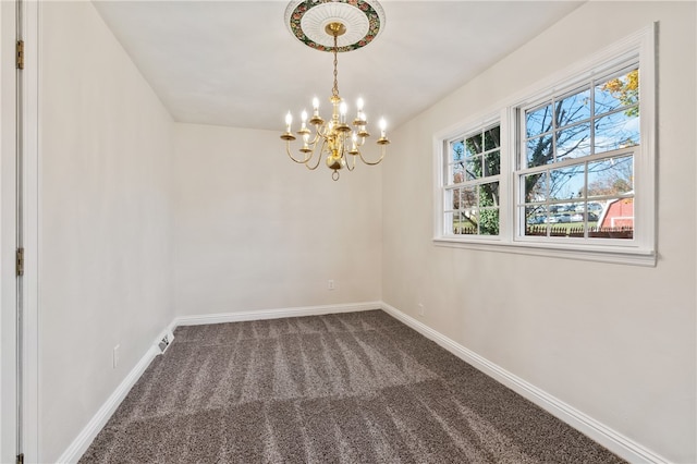 spare room featuring a chandelier and carpet