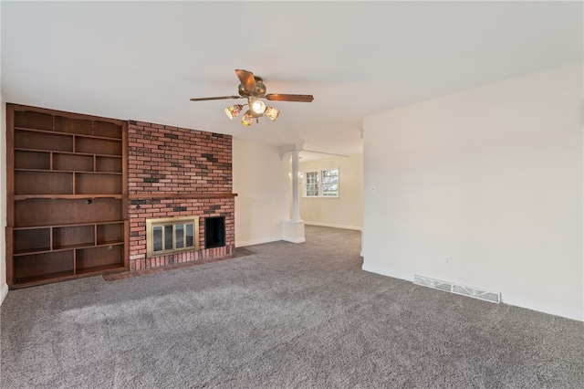 unfurnished living room featuring a fireplace, decorative columns, ceiling fan, and carpet