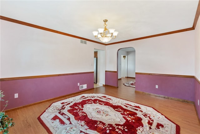 spare room featuring ornamental molding, hardwood / wood-style flooring, and an inviting chandelier