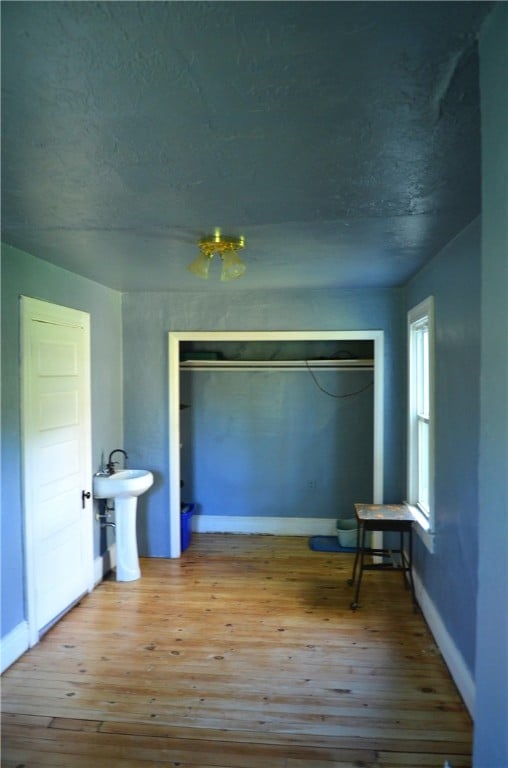 unfurnished bedroom with light wood-type flooring, sink, a closet, and a textured ceiling