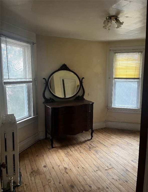 bedroom featuring multiple windows, radiator, and light hardwood / wood-style flooring