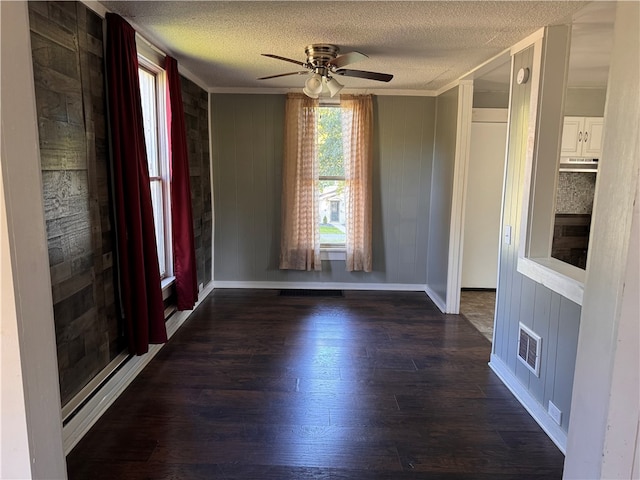 spare room with dark wood-type flooring, wood walls, ornamental molding, and ceiling fan