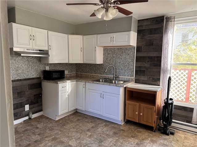 kitchen with a baseboard radiator, white cabinets, sink, ceiling fan, and backsplash