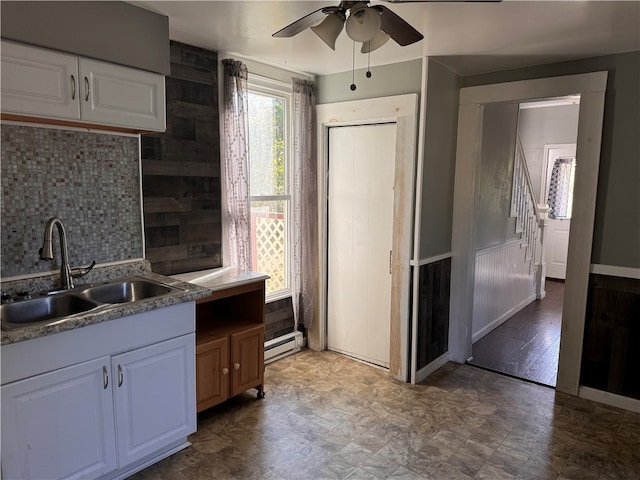 kitchen with tasteful backsplash, wood walls, sink, white cabinets, and ceiling fan