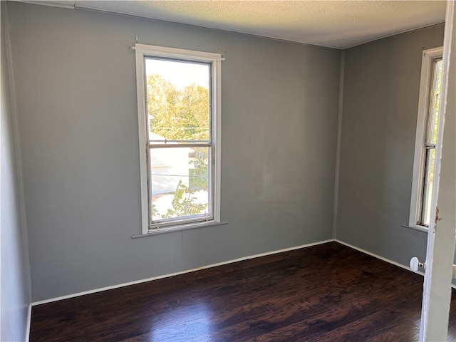 spare room with dark wood-type flooring and a textured ceiling