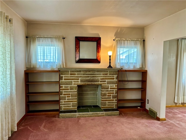 unfurnished living room with a stone fireplace and carpet flooring