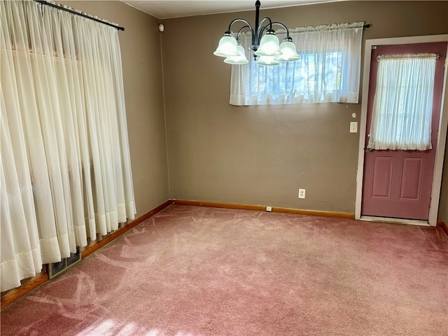 unfurnished dining area featuring a chandelier and carpet