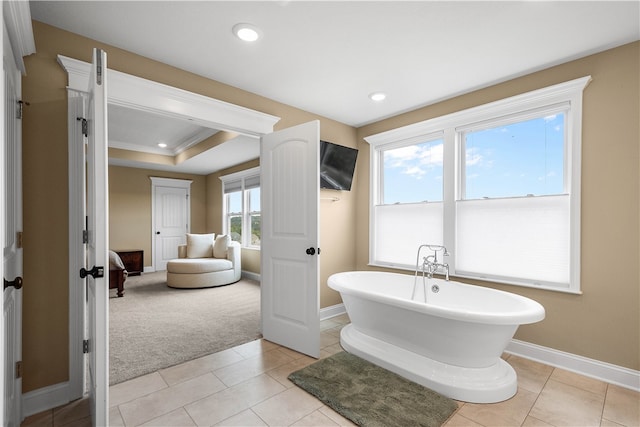 bathroom featuring tile patterned flooring, crown molding, plenty of natural light, and a tub