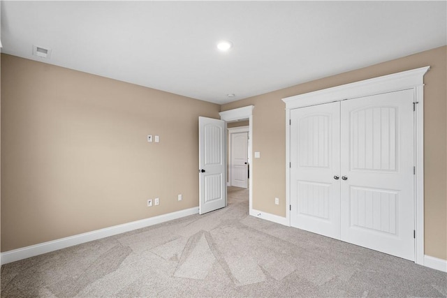 unfurnished bedroom with light colored carpet and a closet