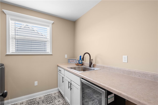 kitchen featuring light tile patterned floors, white cabinetry, sink, and wine cooler