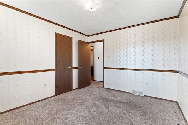 spare room featuring a textured ceiling, light colored carpet, and ornamental molding