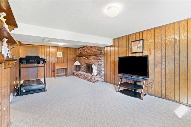 exercise area featuring a brick fireplace, wood walls, light carpet, and a textured ceiling