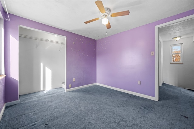 unfurnished bedroom featuring dark colored carpet, ceiling fan, and a closet