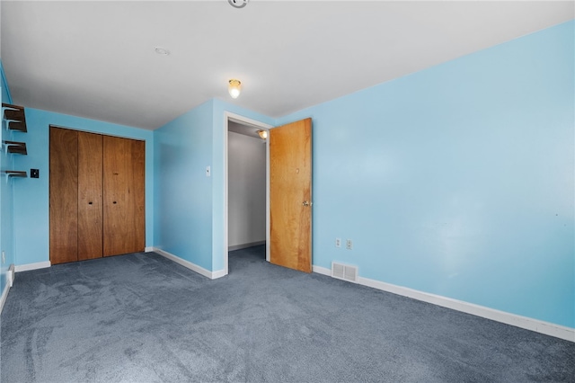 unfurnished bedroom featuring dark carpet and a closet