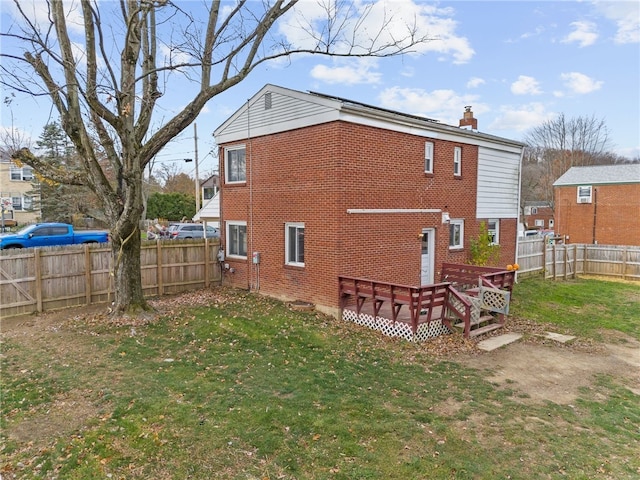 rear view of property featuring a wooden deck and a lawn