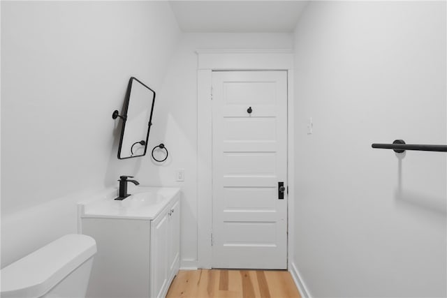 bathroom with hardwood / wood-style floors, vanity, and toilet