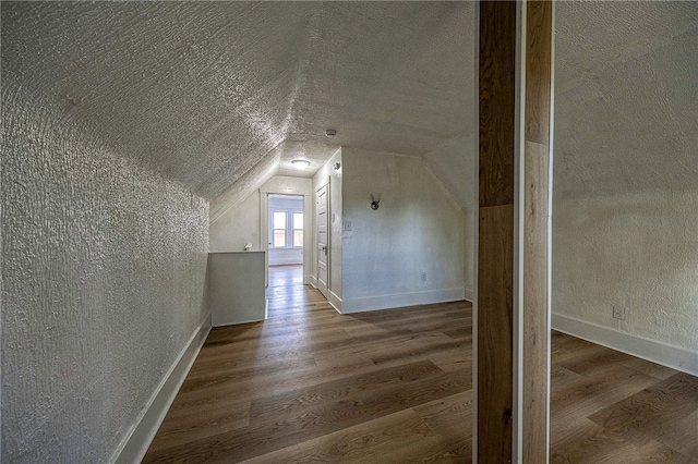 bonus room featuring hardwood / wood-style floors, a textured ceiling, and vaulted ceiling