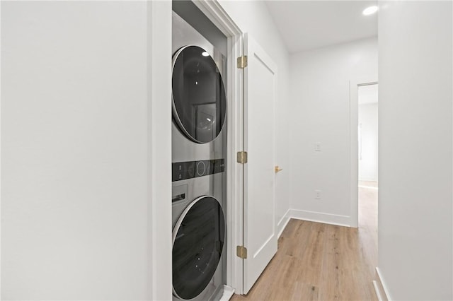 laundry room featuring stacked washer / drying machine and light hardwood / wood-style floors