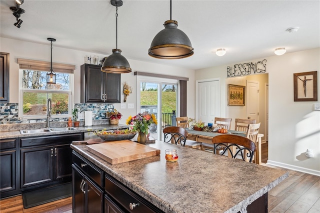 kitchen featuring sink, decorative light fixtures, dark hardwood / wood-style flooring, and a center island