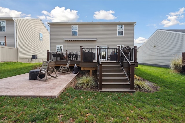 back of property with a yard, a wooden deck, and a patio