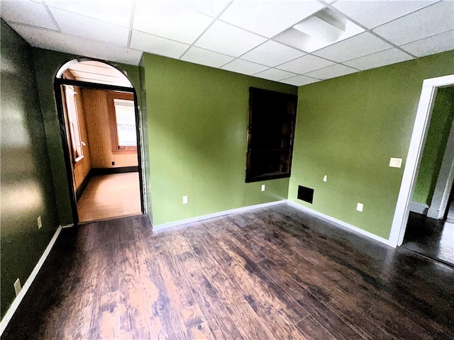 unfurnished room featuring dark hardwood / wood-style flooring and a paneled ceiling