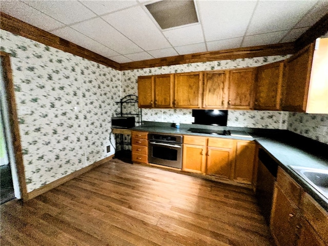 kitchen with appliances with stainless steel finishes, a drop ceiling, and dark wood-type flooring