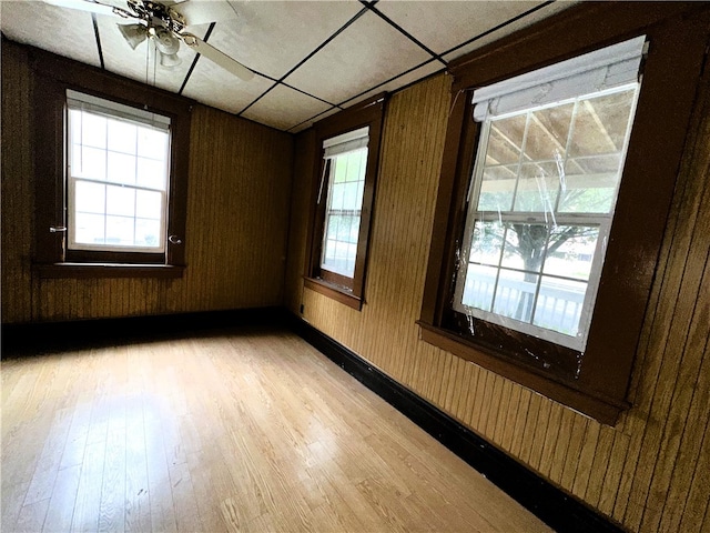 unfurnished room with ceiling fan, wood walls, and light hardwood / wood-style flooring