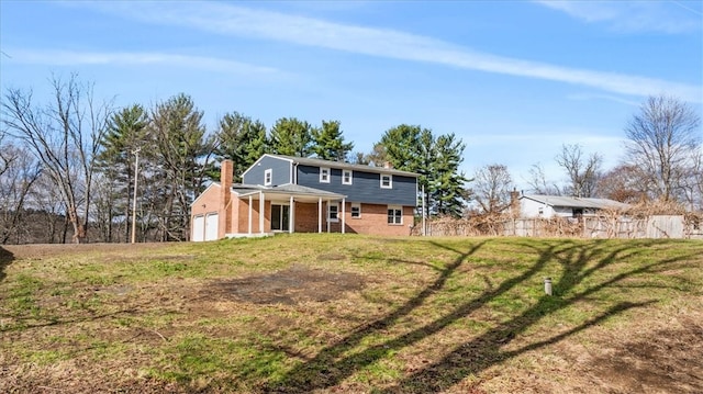 back of house with a garage and a lawn