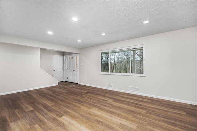 interior space with a textured ceiling and dark hardwood / wood-style flooring